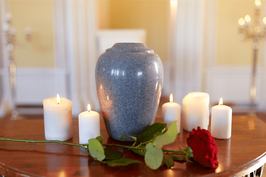 Image of Gray Urn on wooden stand surrounded by candles and flowers