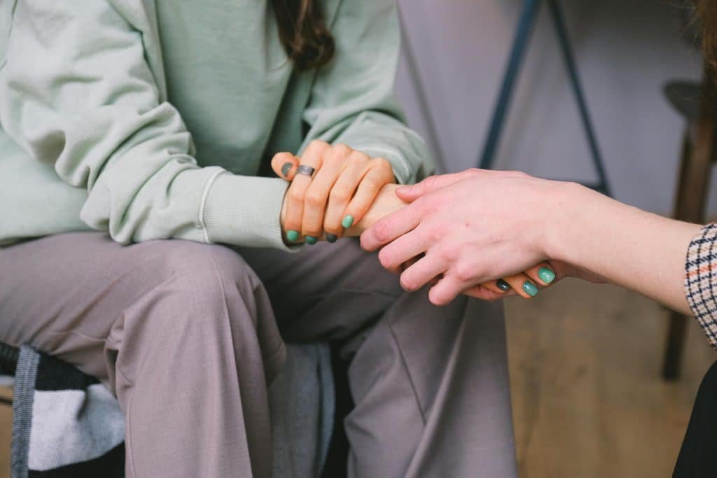 Two people holding hands across from each other discussing pre-planning cremation services